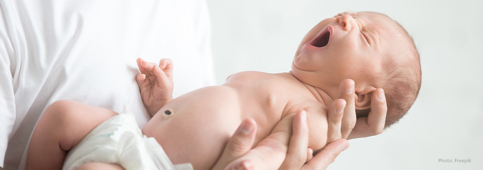 Ein neugeborenes Baby gähnt entspannt, während es auf dem Arm gehalten wird.
